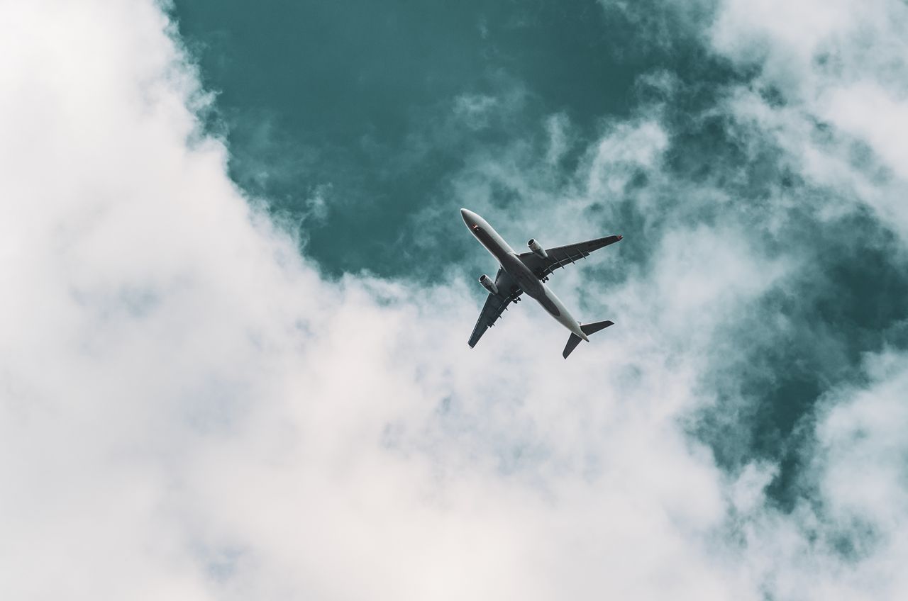A commercial airplane gracefully flying through a dynamic cloudy sky, capturing travel essence.