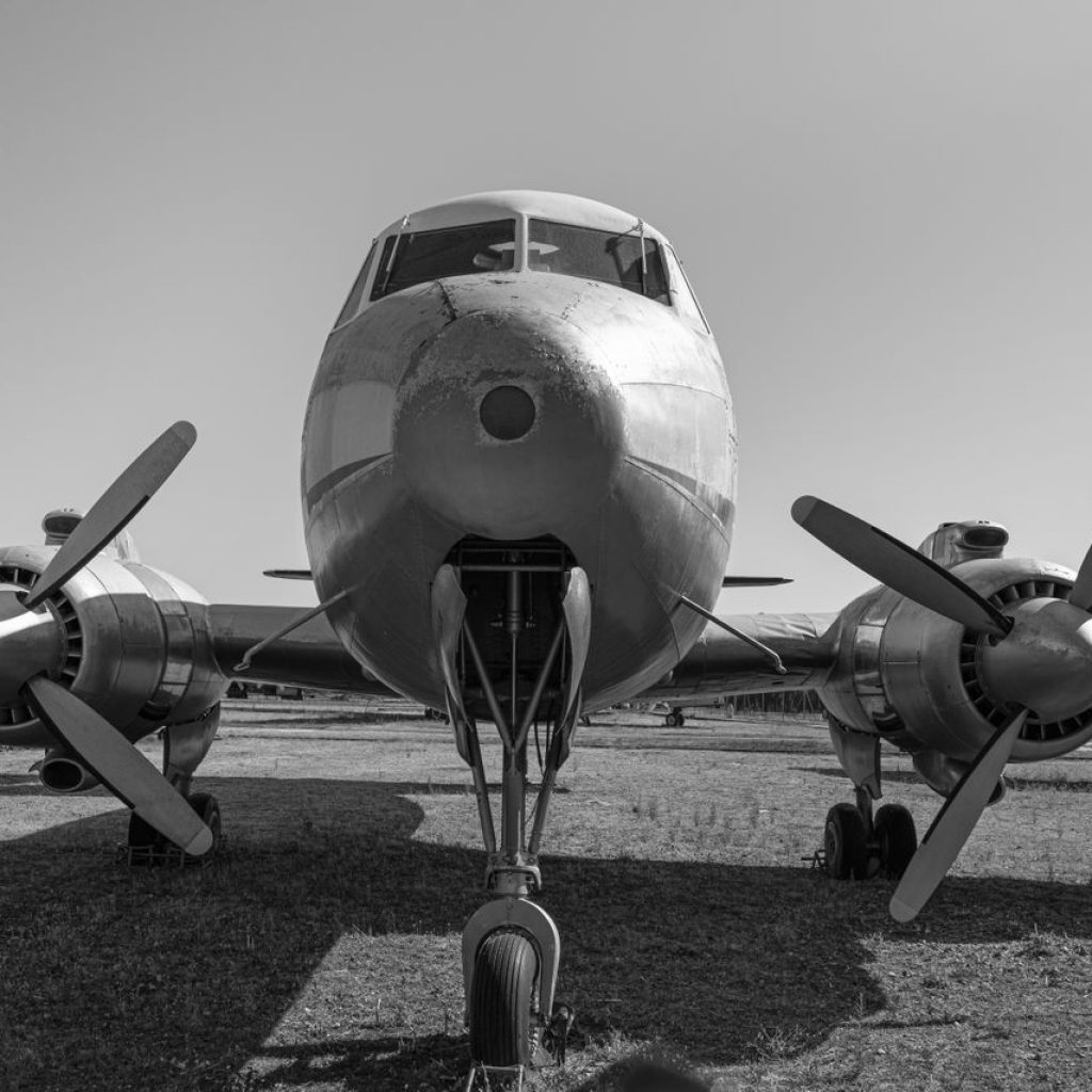A classic vintage biplane with propellers showcased in black and white on a grass runway.