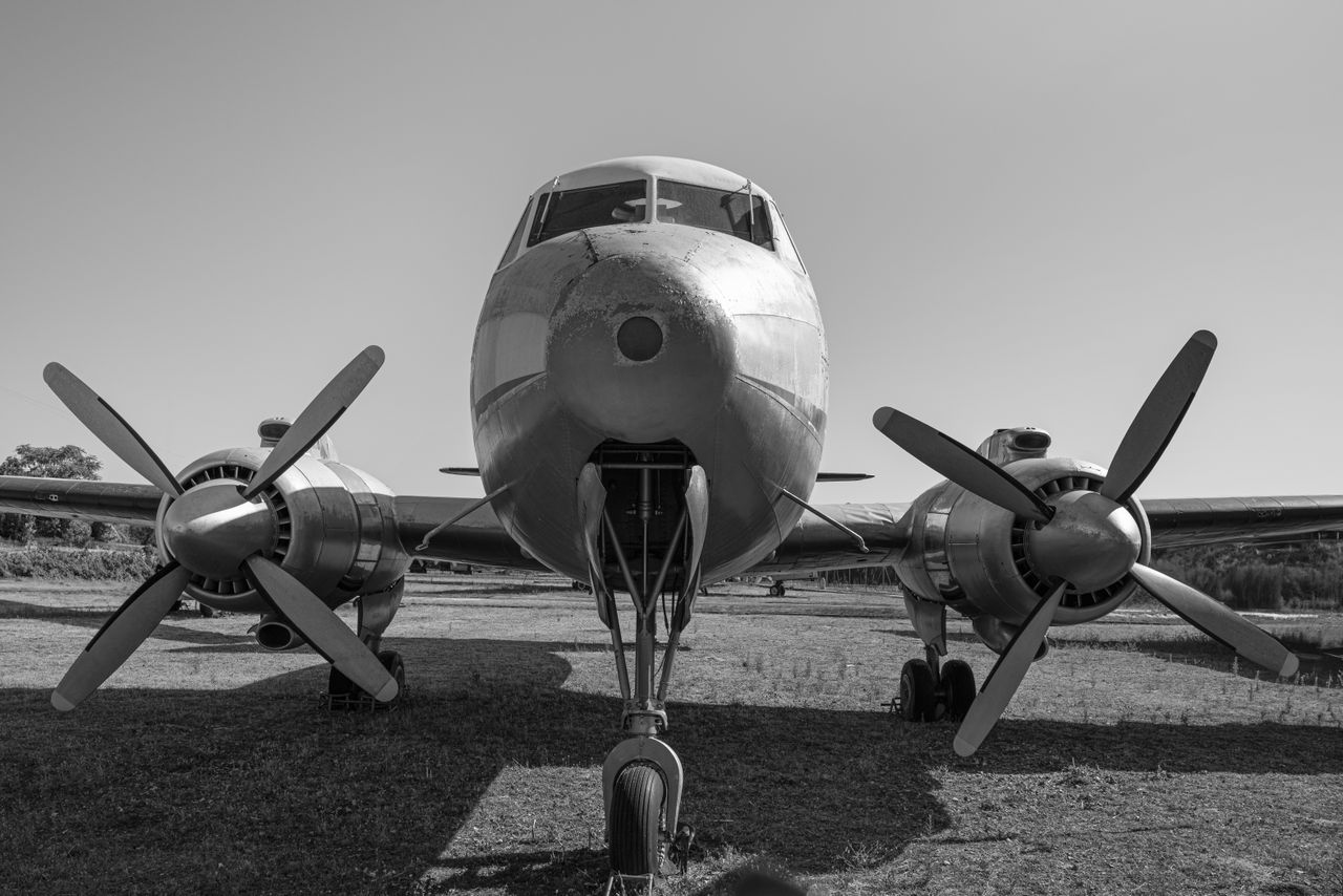 A classic vintage biplane with propellers showcased in black and white on a grass runway.