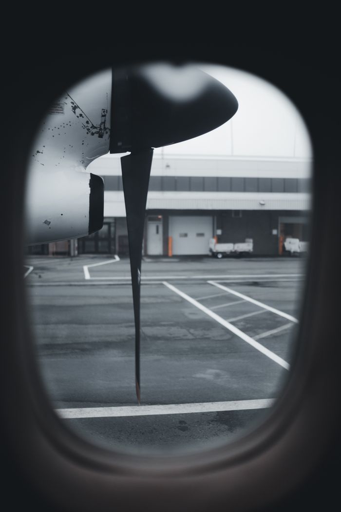Close-up of a propeller seen through an airplane window on a cloudy day at the airport.